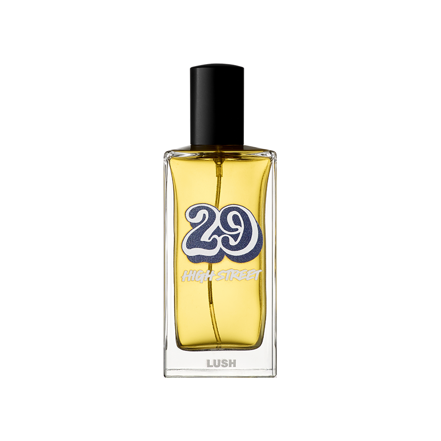 29 High Street. A rectangular glass perfume bottle containing a yellow liquid perfume, featuring a black cylindrical cap. The label shows a large, retro-style blue number '29' with 'HIGH STREET' and the 'LUSH' logo in white text.