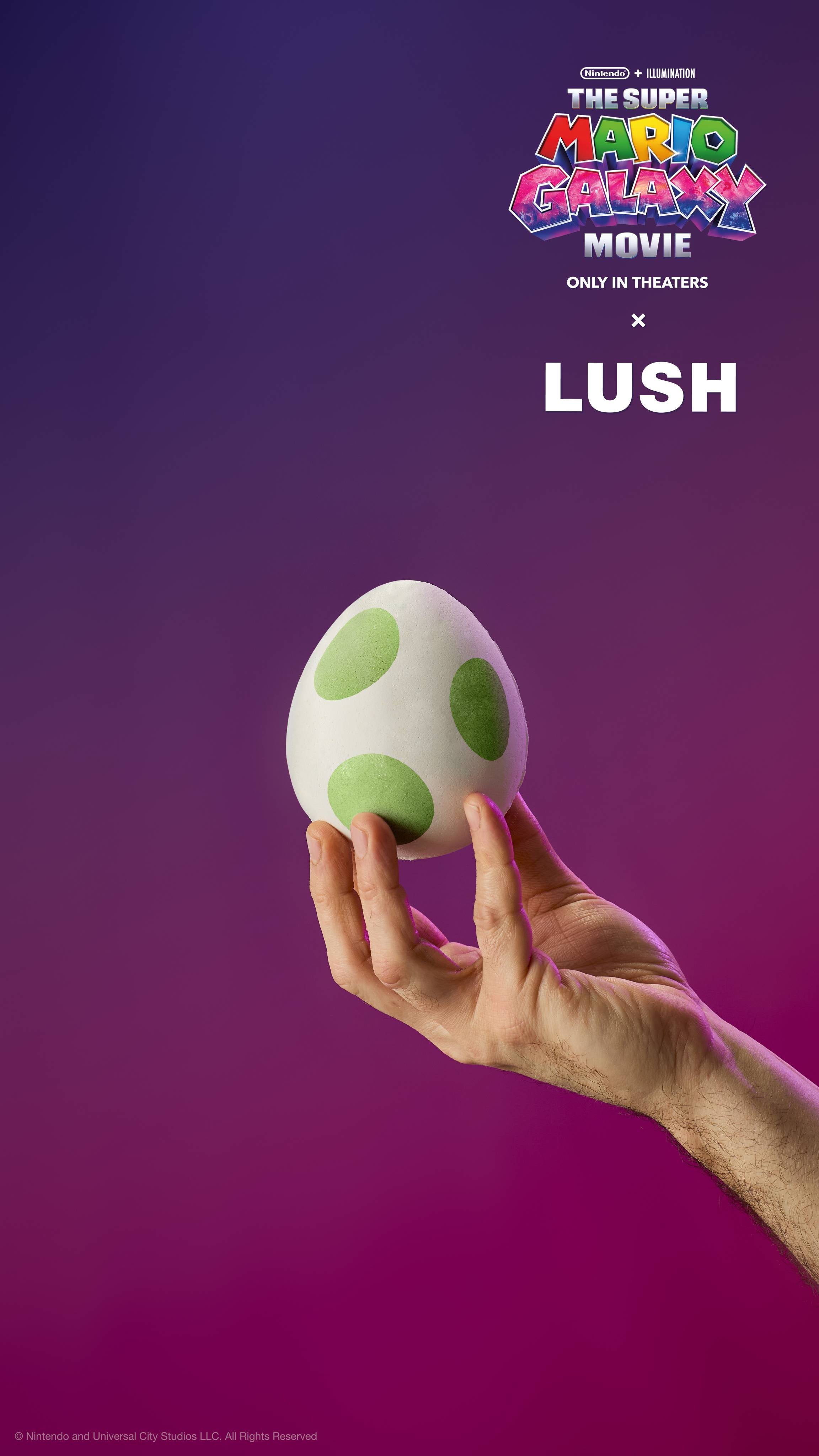 A hand holds a white Yoshi egg bath bomb with green spots against a purple gradient. Text reads "The Super Mario Galaxy Movie x LUSH."