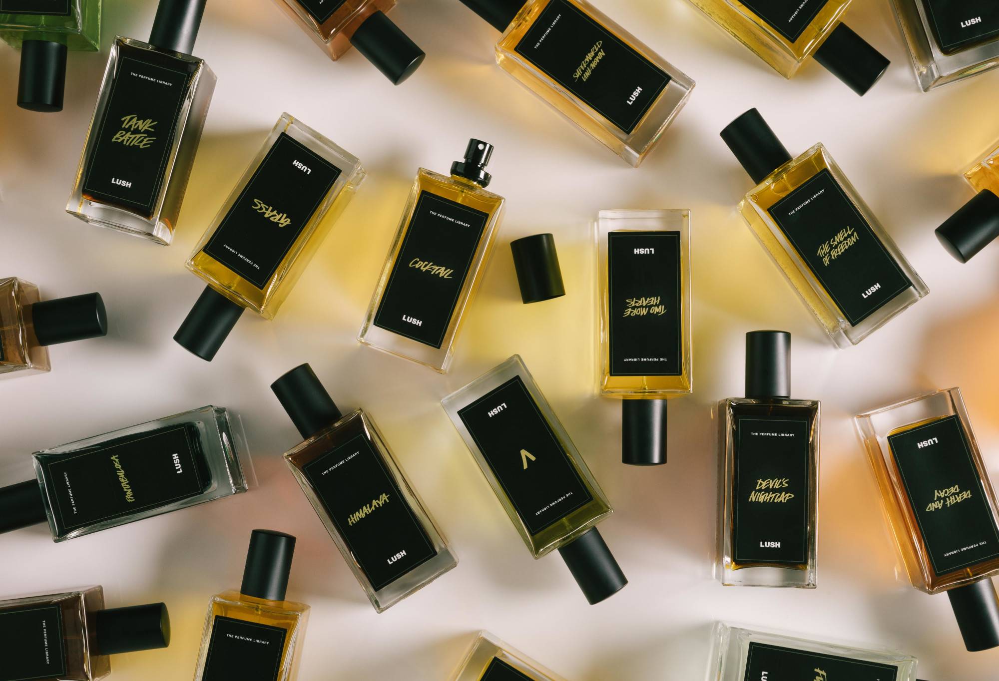 A number of black label perfume bottles are arranged randomly, with Cocktail in the centre, lid off, ready to spritz.
