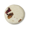 A cream coloured, powdery, circular solid toner tab, pressed with rose petals.
