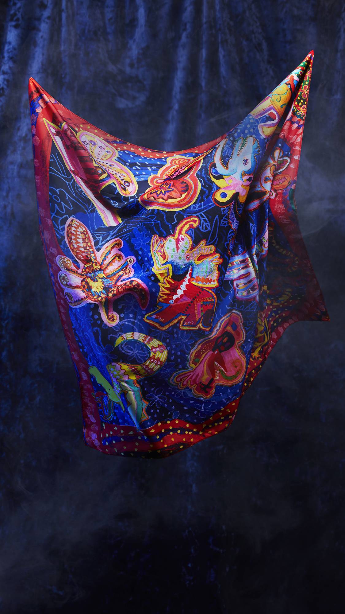 The image shows the Fantasy Animals knot wrap being suspended from the two upper corners, seemingly floating as if by magic. There is a dark, velvet background.