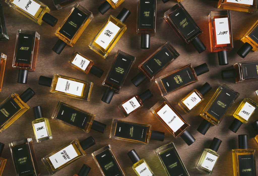 A selection of white and black label perfume bottles are arranged randomly on a dark wooden surface.