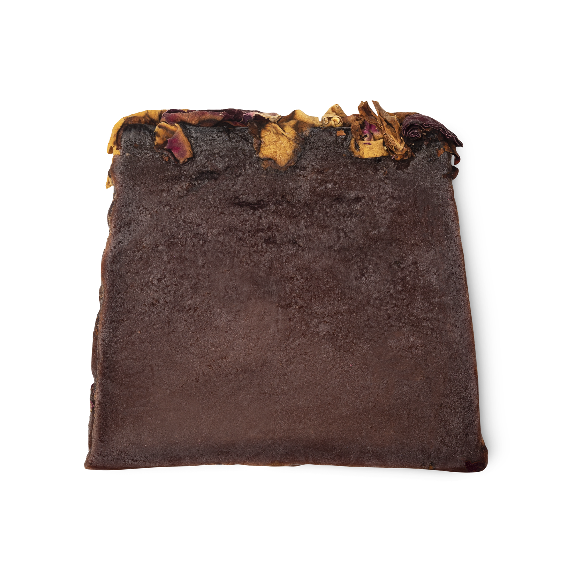 Ro's Argan. A deep purple, moist looking trapezium shaped soap, with a topping of red and yellow rose petals.