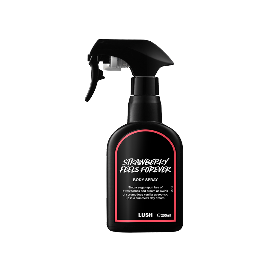 A recycled black plastic LUSH body spray bottle with a trigger nozzle stands upright with a red rimmed label with white text that reads "Strawberry Feels Forever Body Spray".