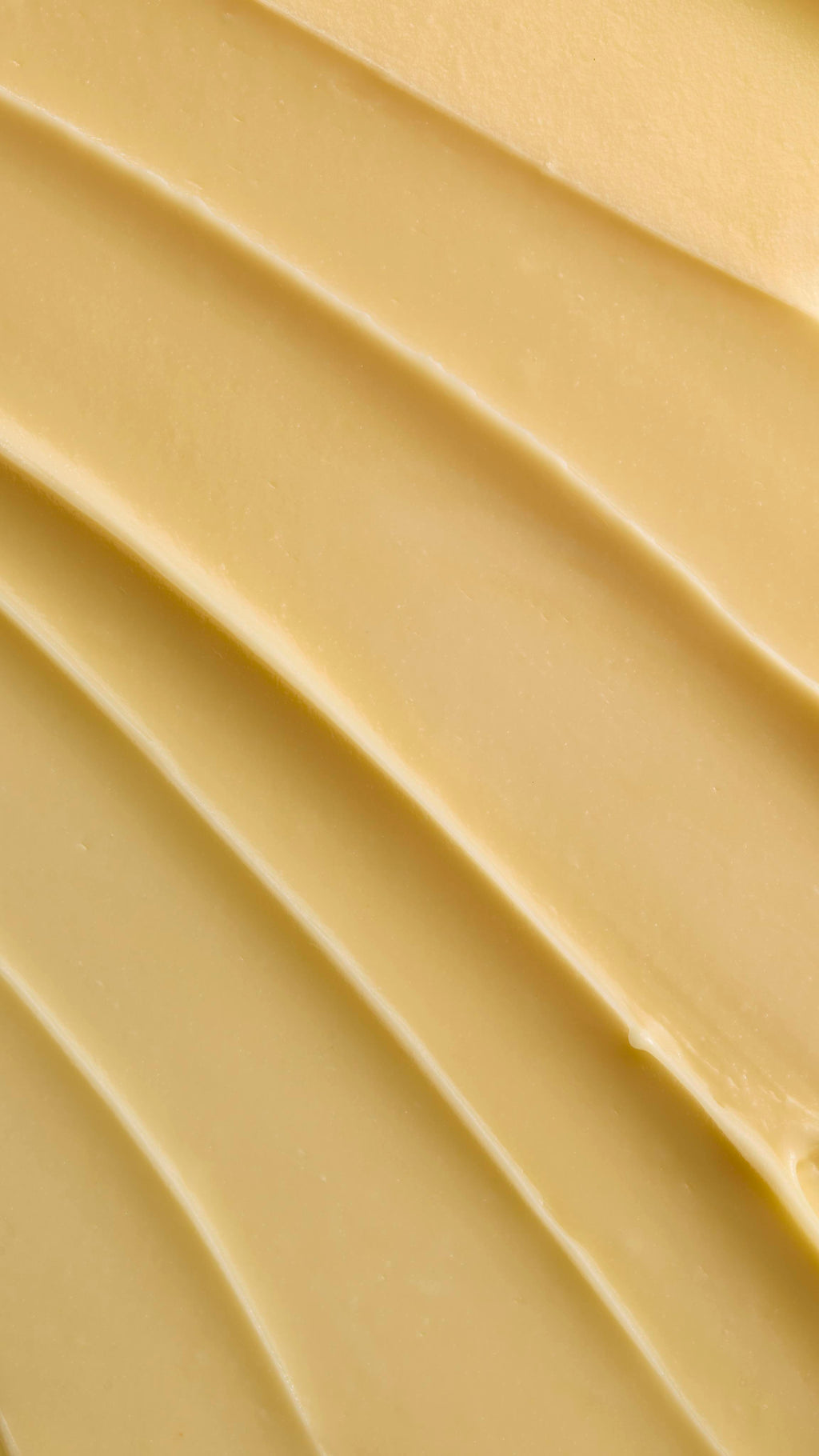 A close-up texture shot of pale yellow Ultrabland cleanser spread out in thick, smooth ridges, highlighting its rich and creamy consistency.