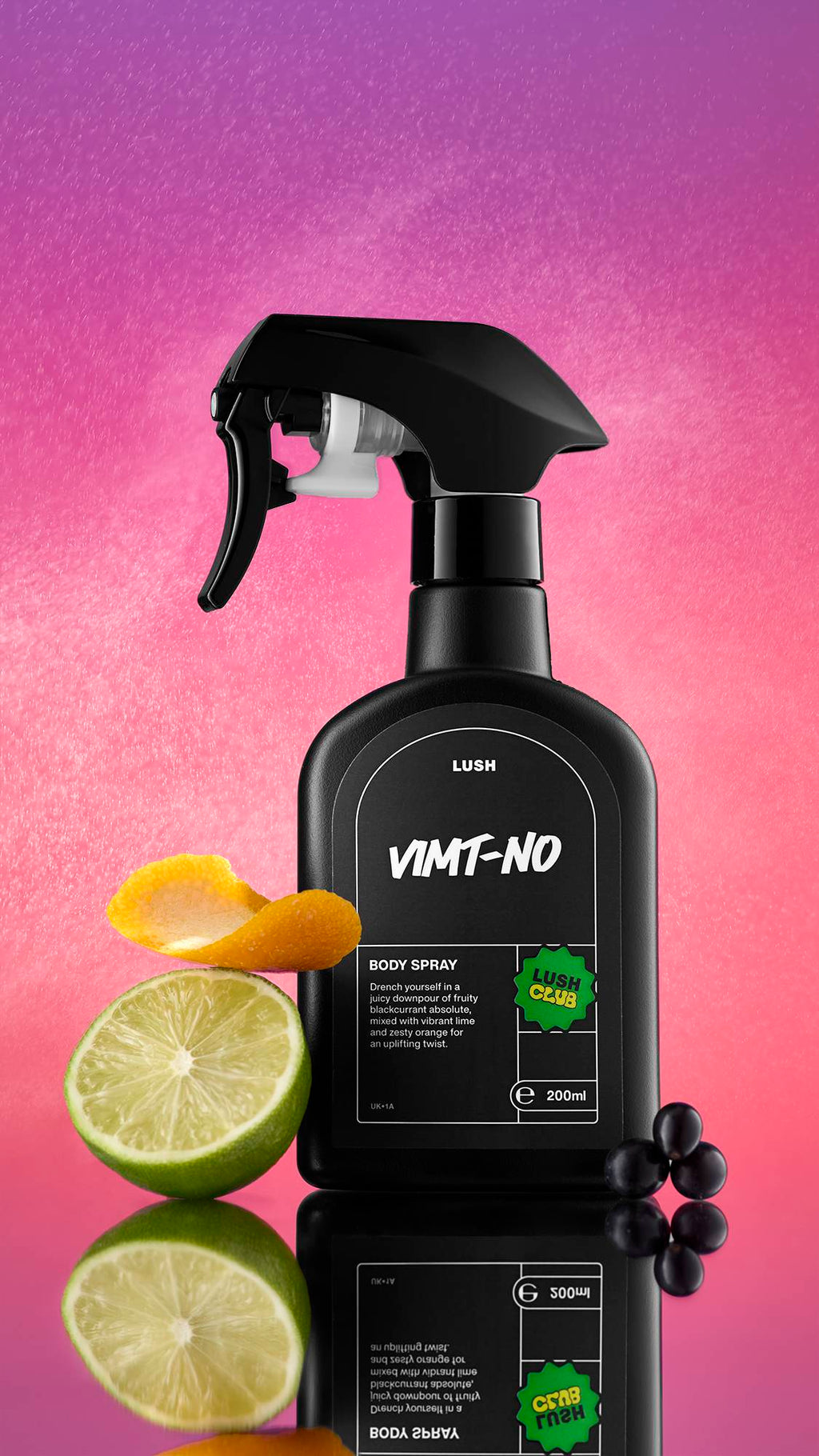 A black spray bottle of VIMT-NO Body Spray stands on a reflective surface against a vibrant pink and purple gradient background with fine water droplets visible. It is flanked by a lime half, a curl of orange peel, and a cluster of black berries.